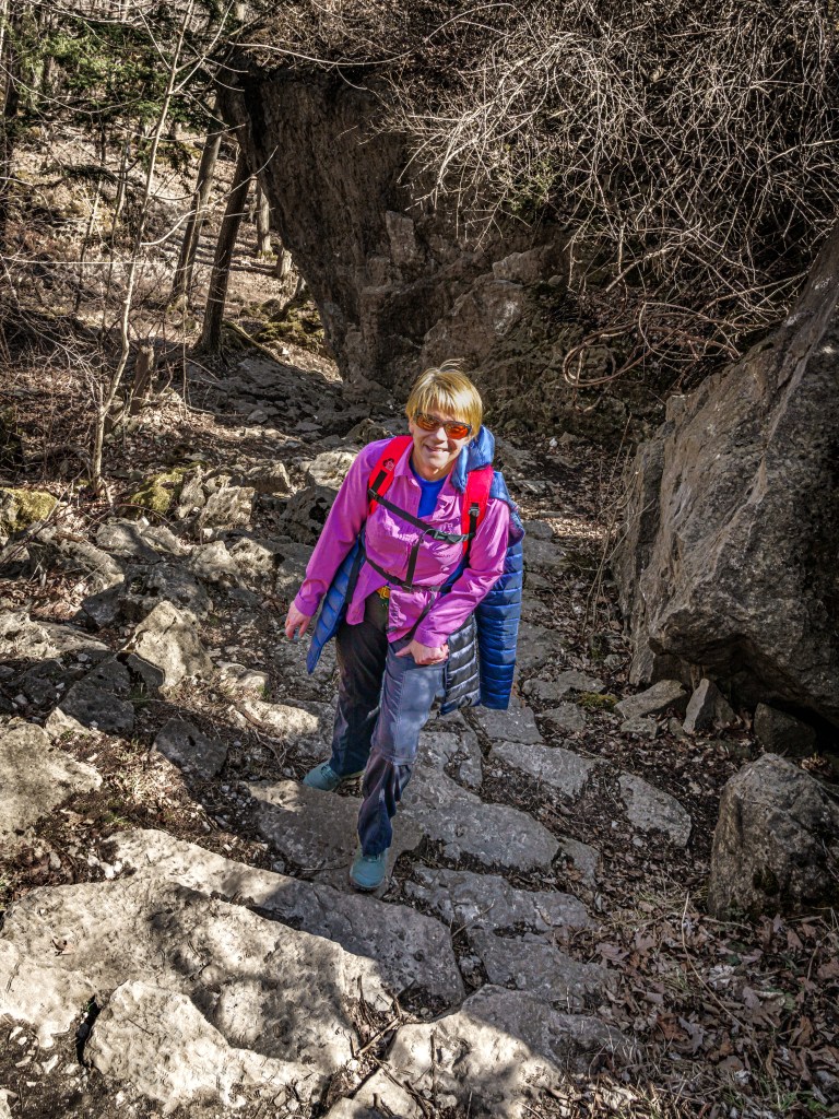 Smiling woman on a rocky trail.